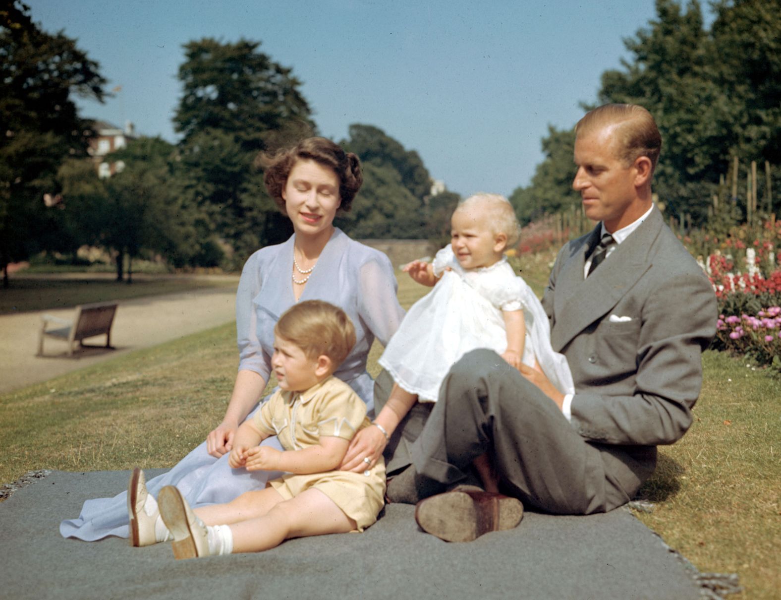 Princess Elizabeth and her husband, Prince Philip, sit on a lawn with their children Prince Charles and Princess Anne in August 1951.