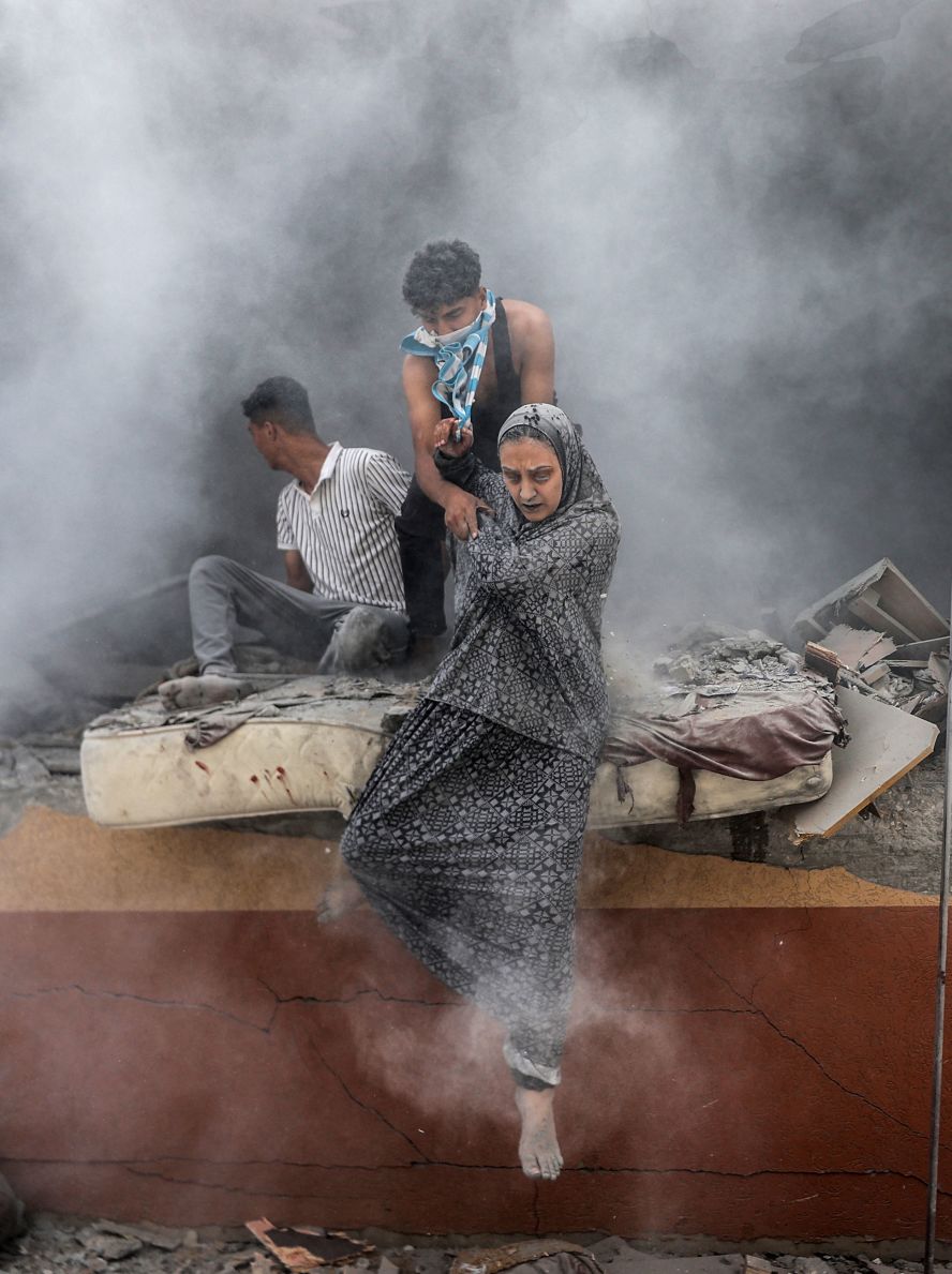 Palestinians walk out of rubble covered in dust after an Israeli attack in Deir al-Balah, Gaza, on Friday, June 14.