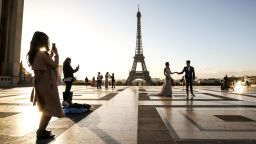 A couple pose for pictures on the Parvis des Droits de l'Homme square in front of the Eiffel Tower on October 1, 2018 in Paris. (Photo by Ludovic MARIN / AFP)        (Photo credit should read LUDOVIC MARIN/AFP/Getty Images)