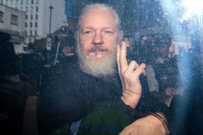 Assange gestures from a police vehicle after arriving at the Westminster Magistrates' Court in London in April 2019.
