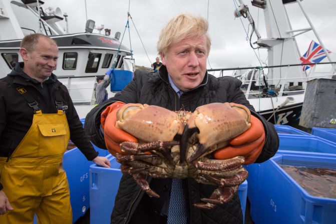 Johnson holds a crab in Stromness Harbour during a visit to Scotland in July 2020.