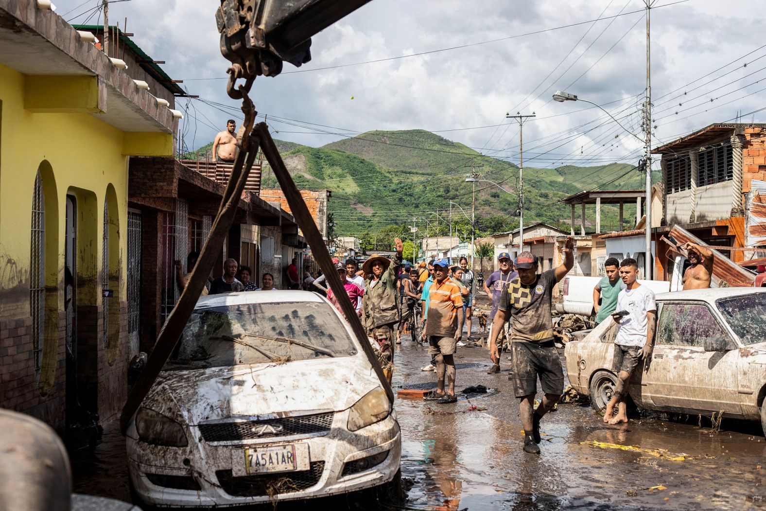 People walk near damaged vehicles in Cumanacoa, Venezuela on Tuesday.