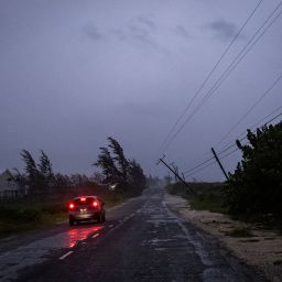 A car in the rain drives past a collapsed post as Hurricane Beryl hits the southern coast of the island, in Kingston, Jamaica, July 3, 2024. REUTERS/Marco Bello 