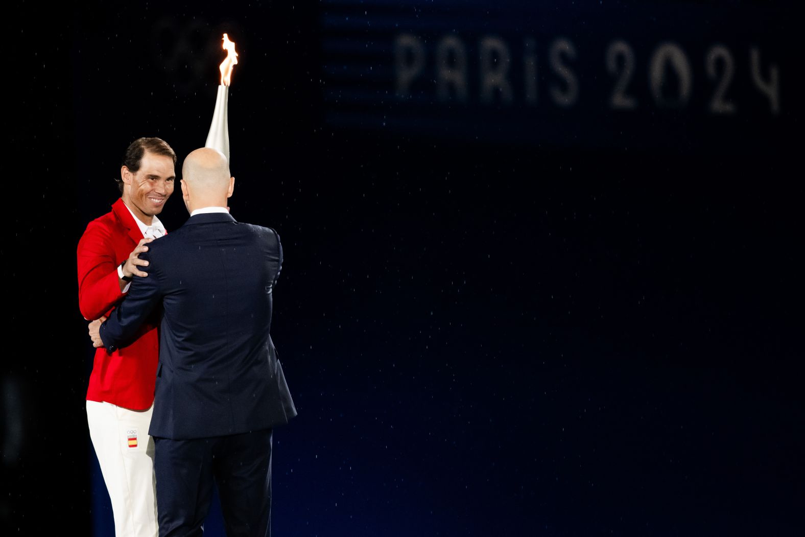 French soccer icon Zinedine Zidane, right, hands off the Olympic torch to Rafael Nadal, <a href="https://www.cnn.com/sport/live-news/paris-olympics-2024-opening-ceremony-seine#h_249177297f865db4aab2621e59ee0965">the Spanish tennis star</a> who has won two Olympic gold medals and a record 14 French Opens. The torch passed to various athletes before ending up with Riner and Pérec.