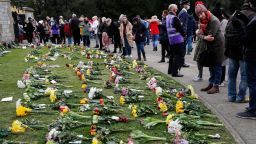 People view flower tributes at Cambridge Gate, at Windsor Castle, one day after the death of Britain's Prince Philip, in Windsor, England, Saturday, April 10, 2021. Britain's Prince Philip, the irascible and tough-minded husband of Queen Elizabeth II who spent more than seven decades supporting his wife in a role that mostly defined his life, died on Friday. (AP Photo/Frank Augstein)