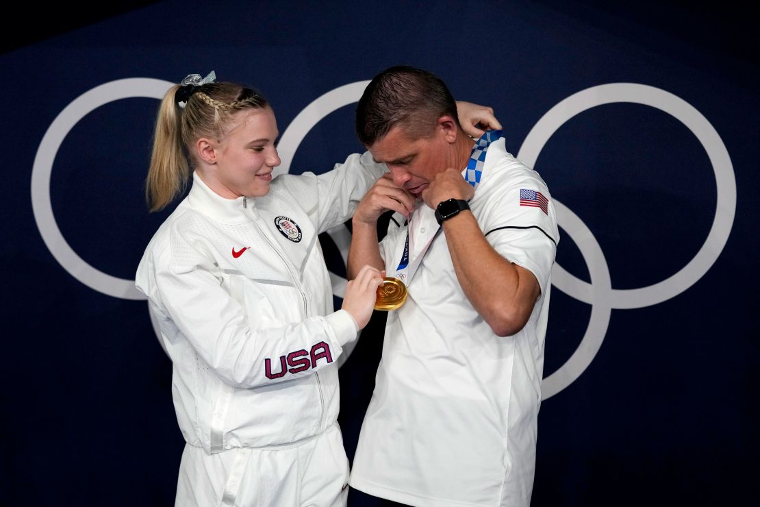 Carey places her gold medal for the floor exercise over the neck of her dad and coach, Brian Carey.