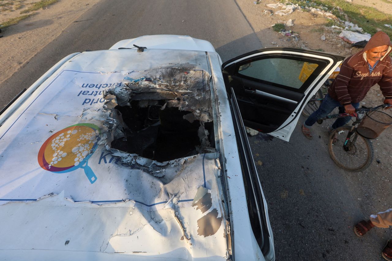 A Palestinian man rides a bicycle past a damaged vehicle where employees from the World Central Kitchen were killed in an Israeli airstrike in Deir Al-Balah, central Gaza, on April 2.