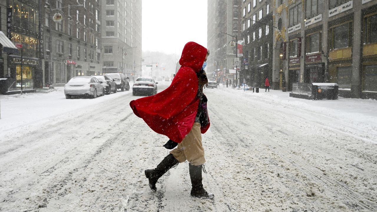 A woman in a red cape crosses 57th Street during a winter storm that brought more than 7 niches of snow and heavy wind gusts to the city, New York, NY, January 29, 2022. New York City is under a hazardous travel advisory as a Nor'easter knocks out power in the Northeast and brings heavy snow across the region. (Photo by Anthony Behar/Sipa USA)(Sipa via AP Images)