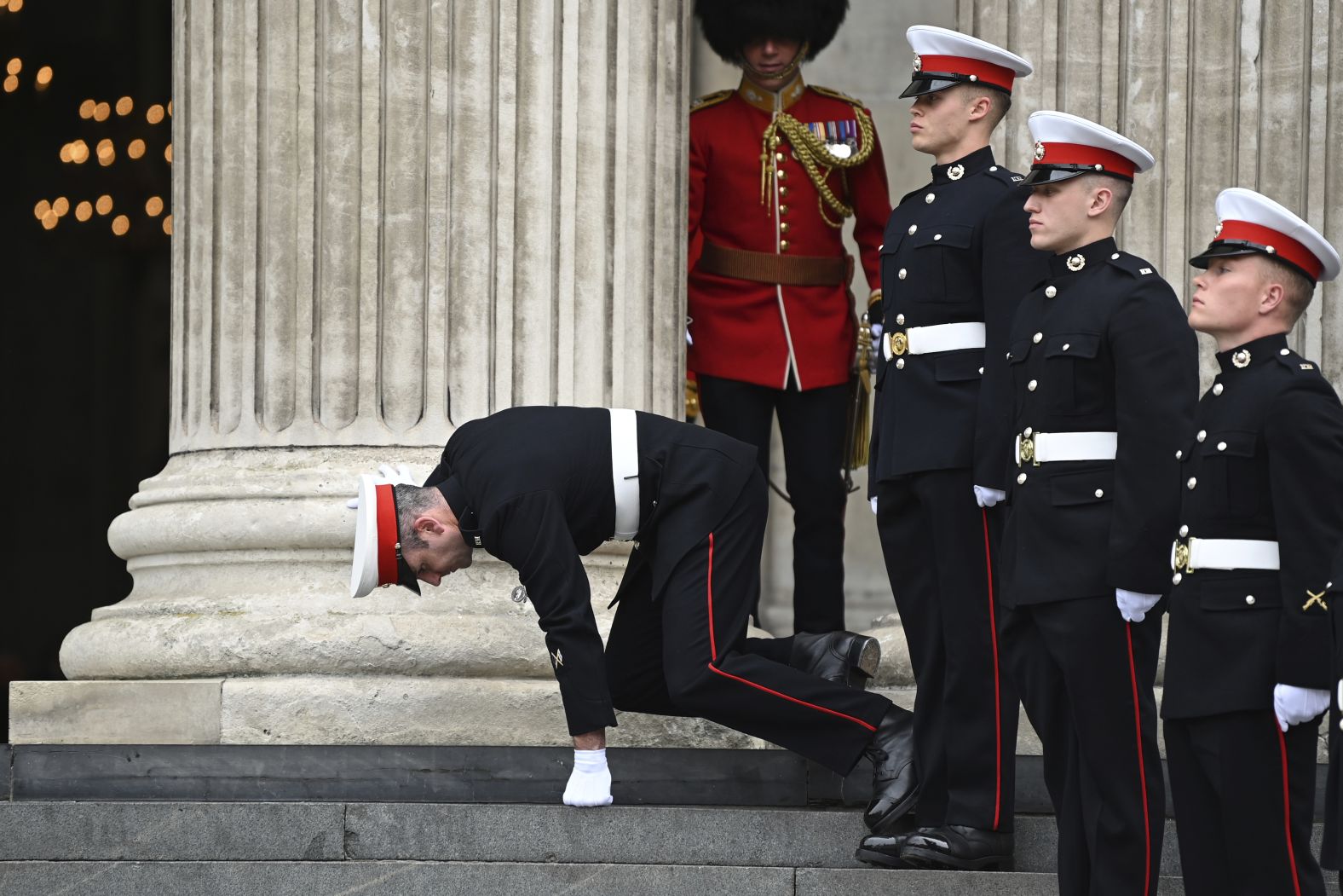 A member of the military stumbles Friday while on duty ahead of the service.