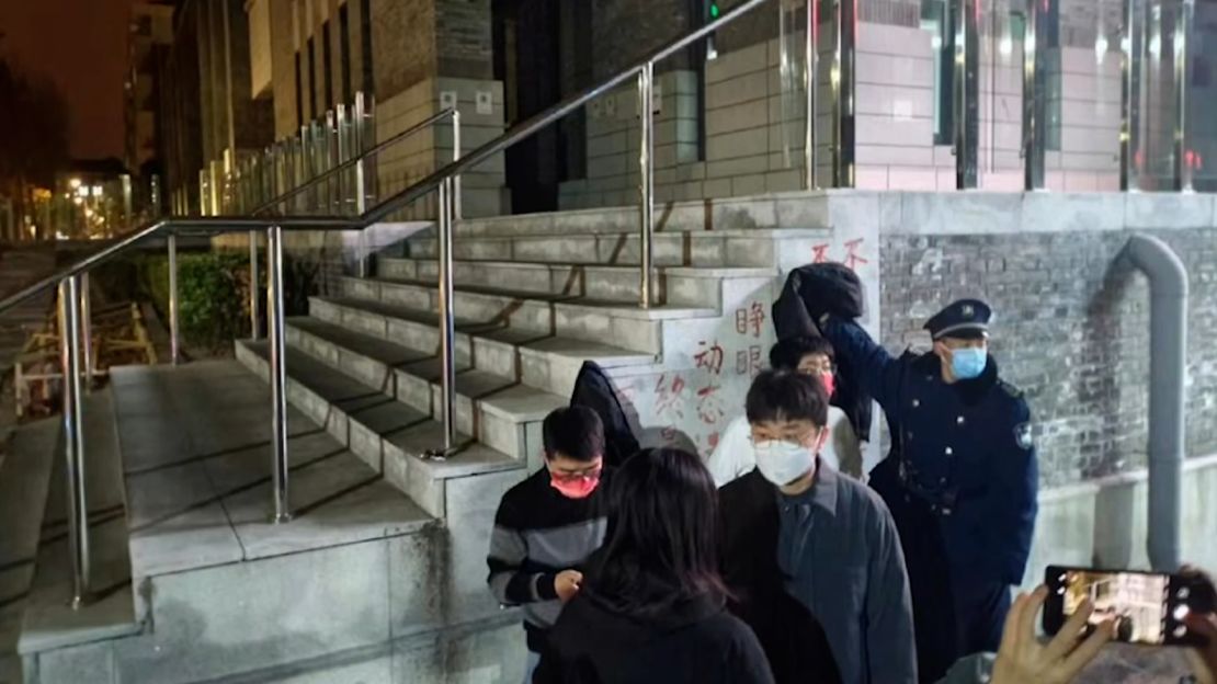 A security guard tries to cover a protest slogan against zero-Covid on the campus of Peking University in Beijing.