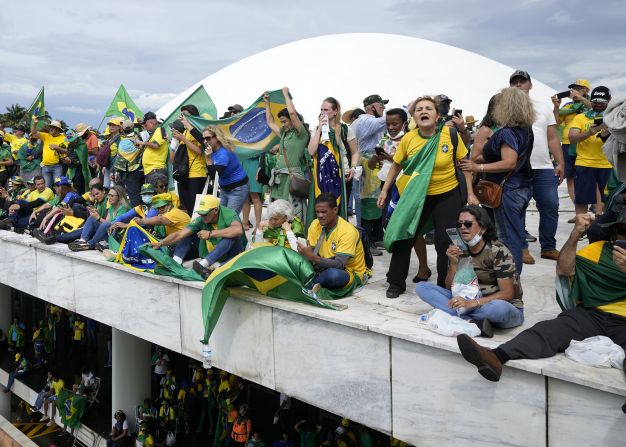 Supporters of former President Jair Bolsonaro stand on the roof of the National Congress building.