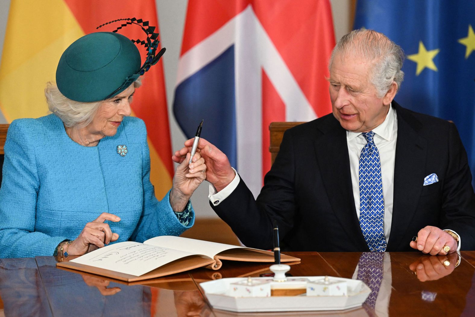 The King and Camilla, the Queen Consort, sign a guest book Wednesday at the palace.