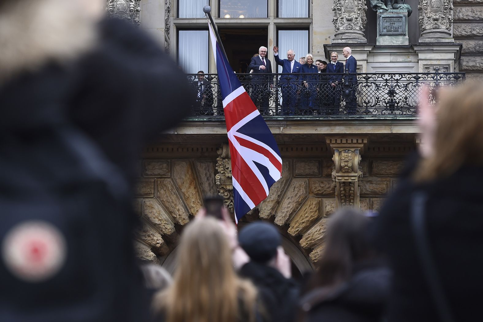 The King waves from a balcony at Hamburg's City Hall.