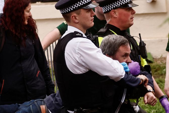 Police officers detain a protester ahead of the King's procession. <a href="https://www.cnn.com/uk/live-news/king-charles-iii-coronation-ckc-intl-gbr/h_089ce3083553388e9051d6c7fd26c7b0" target="_blank">Several arrests were made Saturday</a> as protesters gathered near the procession route.