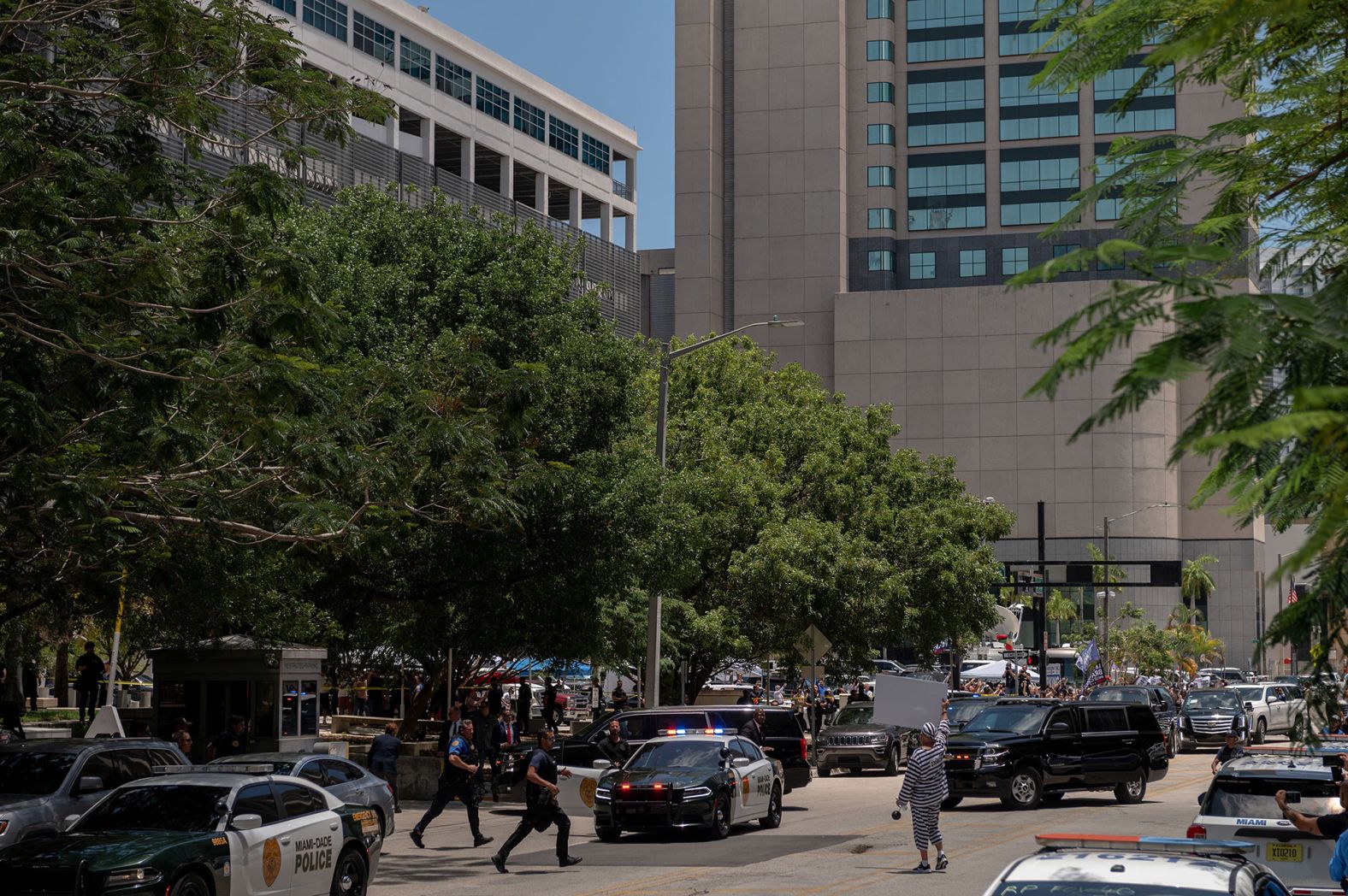 Police rush to move a protester who was holding a sign in the street as Trump's motorcade arrived at the federal courthouse in Miami.