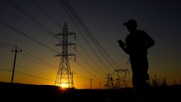 A jogger passes under power lines during an evening run, Monday, June 26, 2023, in San Antonio. Meteorologists say scorching temperatures brought on by a heat dome have taxed the Texas power grid and threaten to bring record highs to the state.