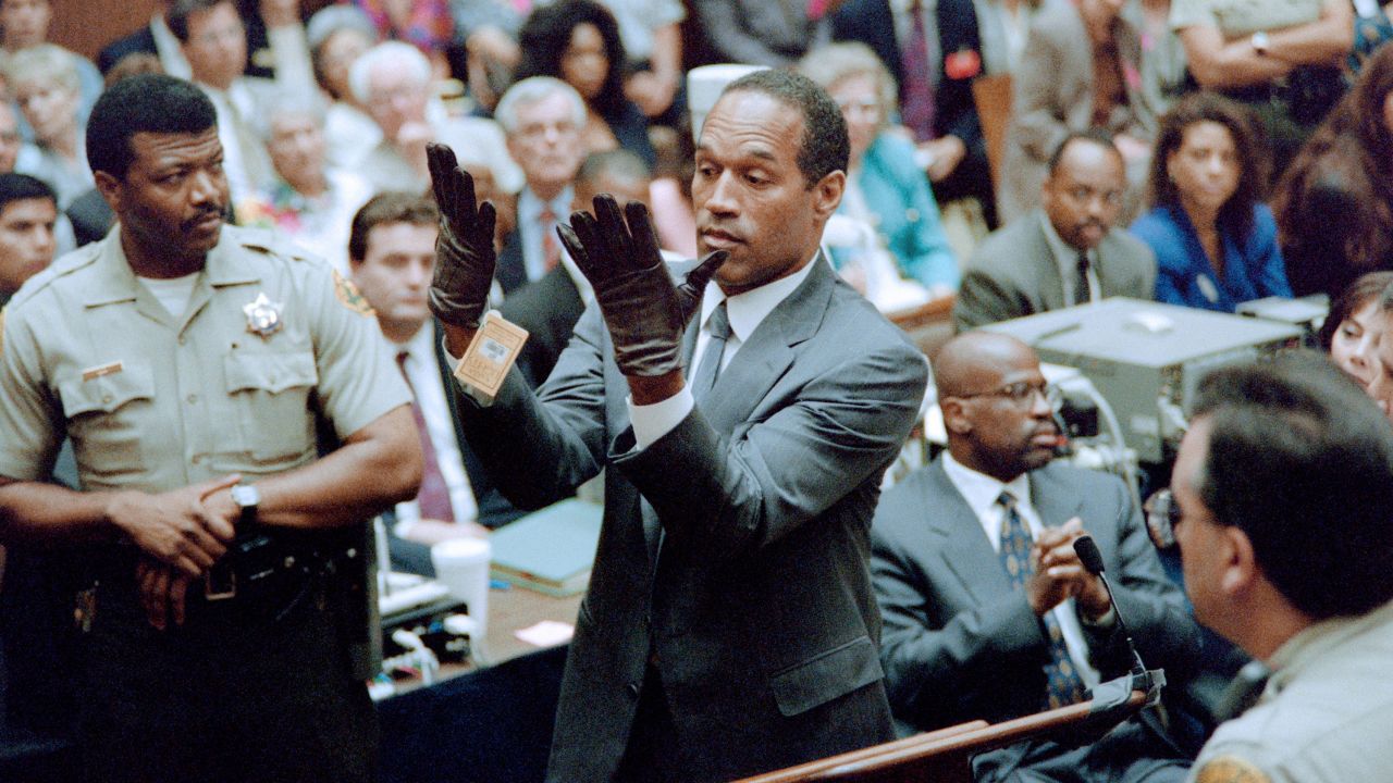 O.J. Simpson looks at a new pair of Aris extra-large gloves which the prosecutors had him put on for the jury 21 June 1995 during his double murder trial in Los Angeles. The gloves were the same type found at the Bundy murder scene and the O.J. Simpson estate. 