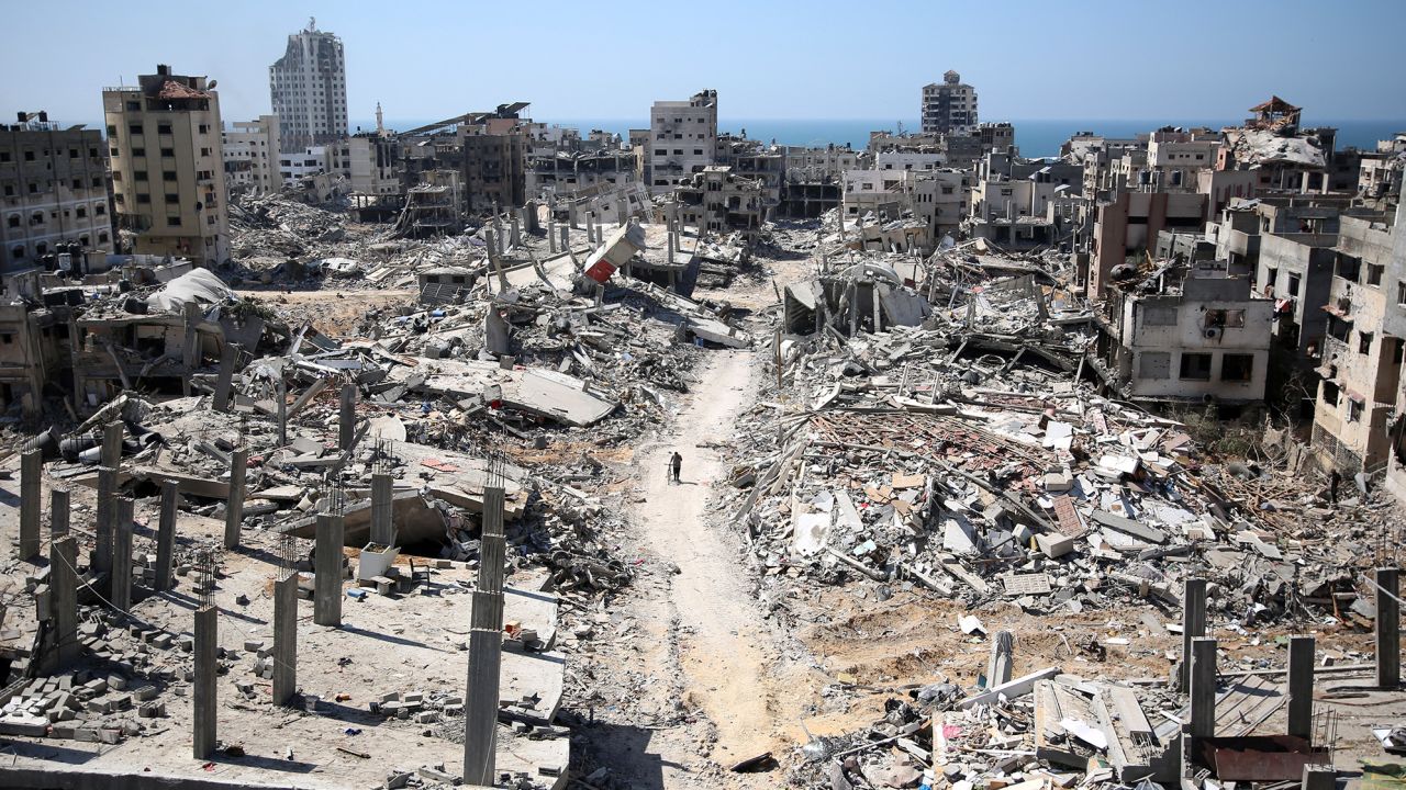 TOPSHOT - A man pushes a bycicle along as he walks amid building rubble in the devastated area around Gaza's Al-Shifa hospital on April 3, 2024, amid the ongoing conflict between Israel and the Palestinian Hamas militant group. (Photo by AFP) (Photo by -/AFP via Getty Images)