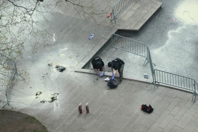 New York police officers inspect a backpack after <a href="https://www.cnn.com/politics/live-news/trump-hush-money-trial-04-19-24/h_a0c5ea747751ddad7bc88749d2f559d1" target="_blank">a man lit himself on fire</a> in a park outside the courthouse in Manhattan on April 19.