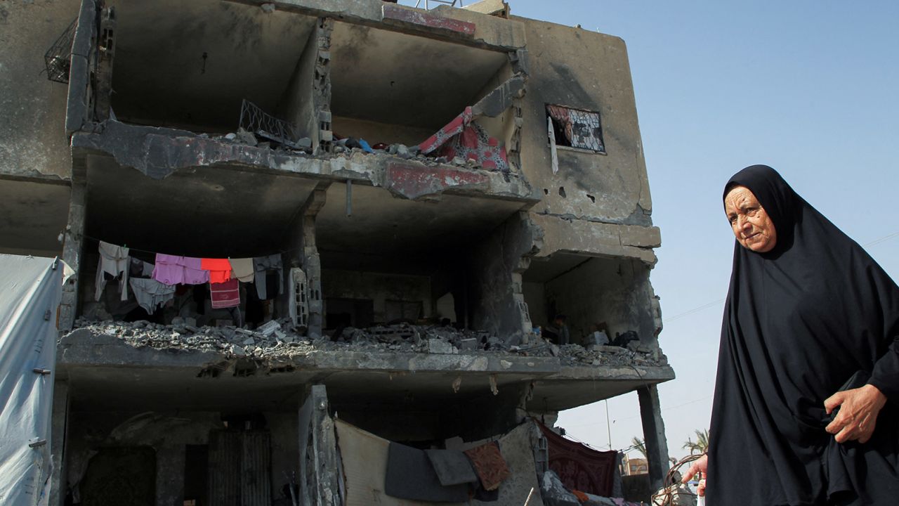 A Palestinian woman walks past a house destroyed by an Israeli strike, in Rafah, on May 22, 2024. 