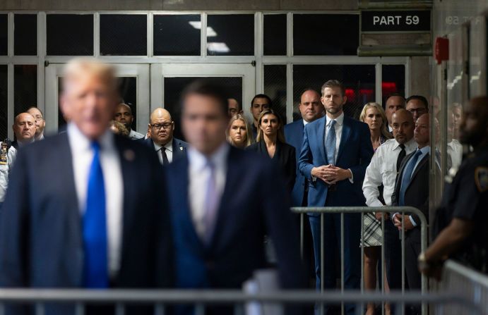 Trump's son Eric, seen fourth from the right with his fingers interlocked, listens as his dad speaks to the media after the verdict.