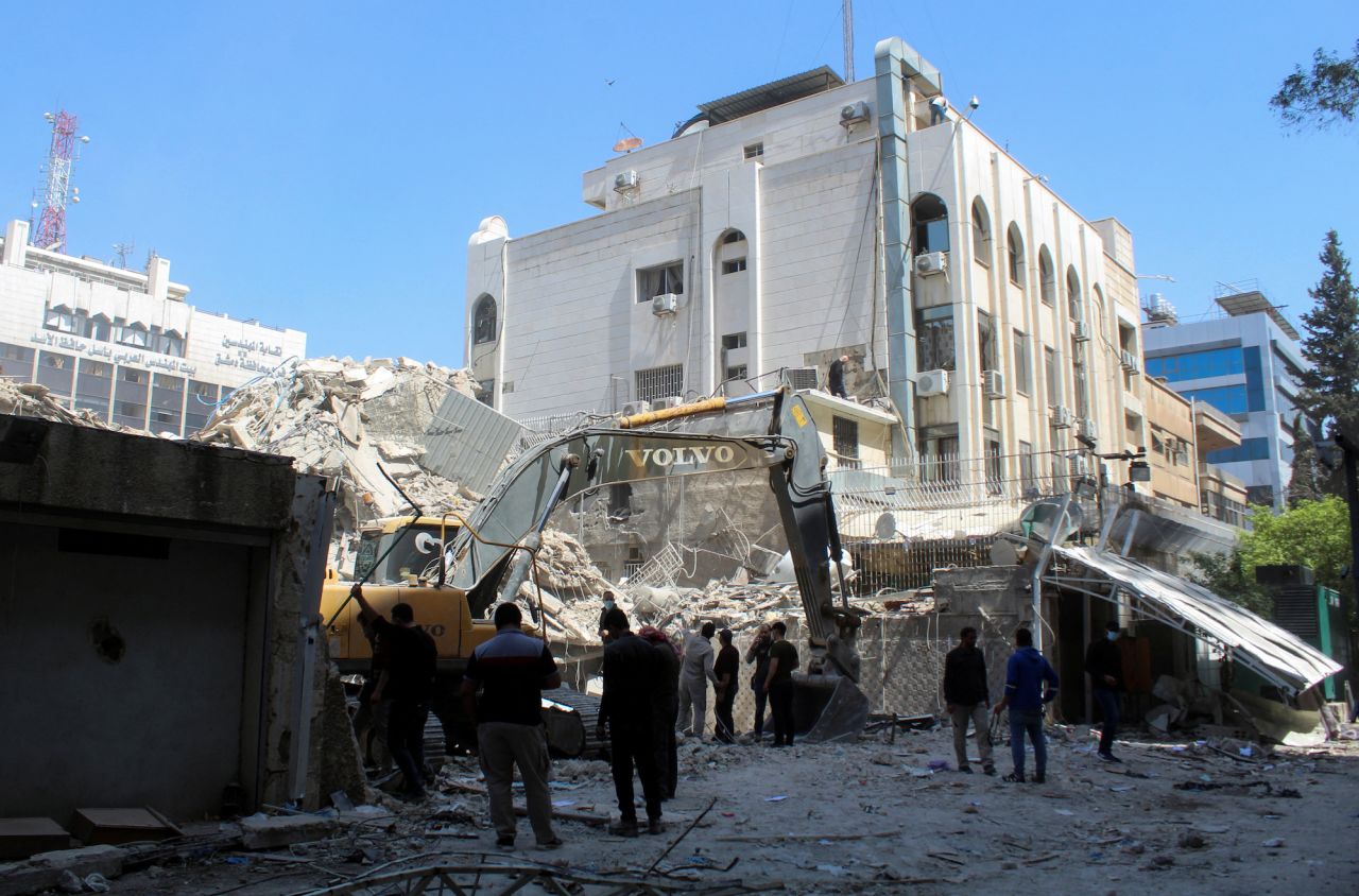 People gather as an excavator clears rubble after a suspected Israeli airstrike on Iran's consulate in the Syrian capital of Damascus on April 2.