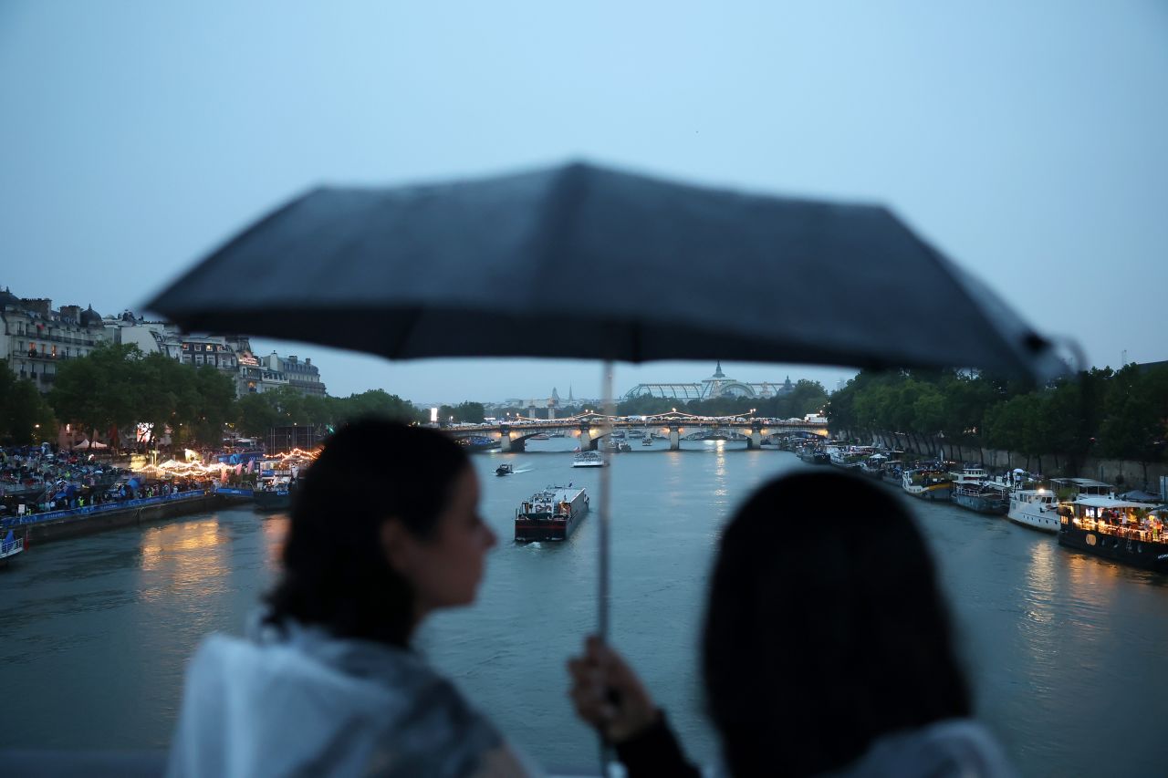 Athlete boats travel along the River Seine as spectators shelter from the rain during the opening ceremony of the Olympic Games Paris 2024 on July 26.