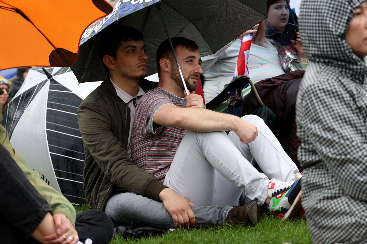 People watch Britain's King Charles and Queen Camilla's coronation ceremony at Westminster Abbey on a screen.