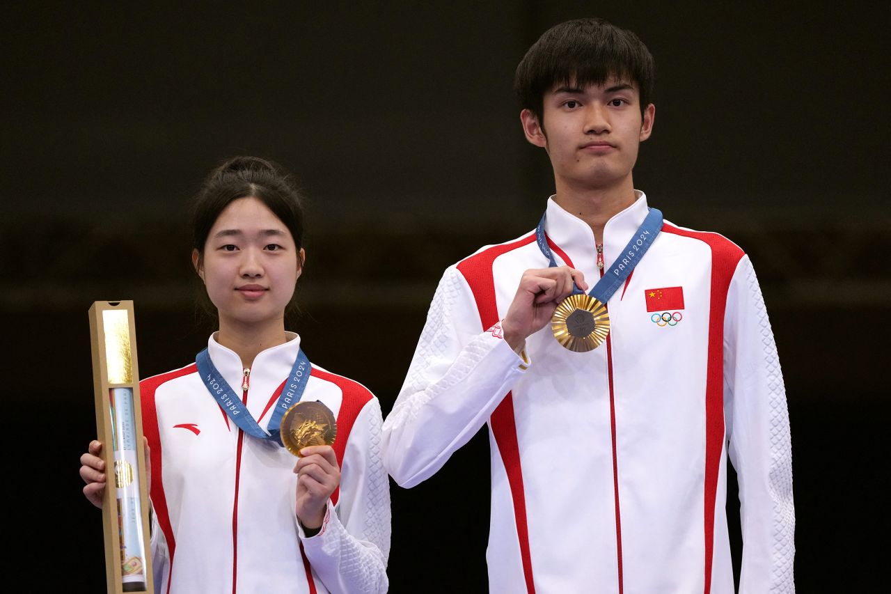 China’s Huang Yuting, left, and Sheng Lihao pose with their gold medals on July 27. They won the 10-meter air rifle mixed-team shooting competition.