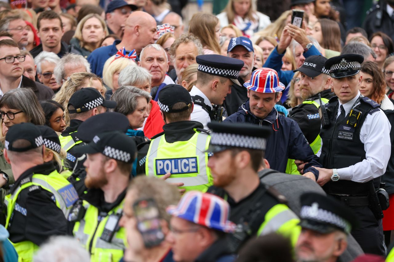 Police officers detain an individual wearing a British Union flag hat in London on Saturday.