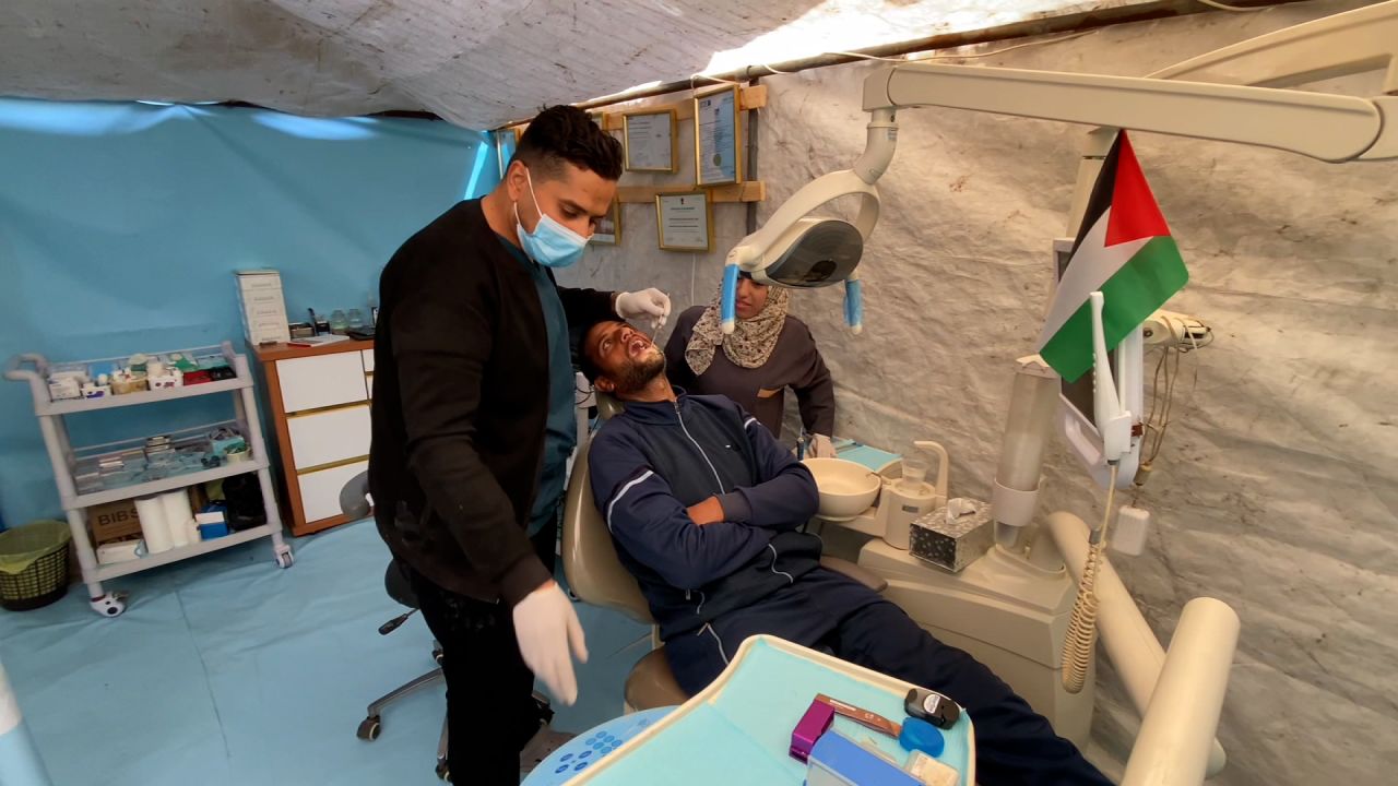 Najdat Mohammed Saqer, left, treats a patient inside the tent clinic inside a tent in Deir al-Balah, in central Gaza, in the northern Nuseirat refugee camp.