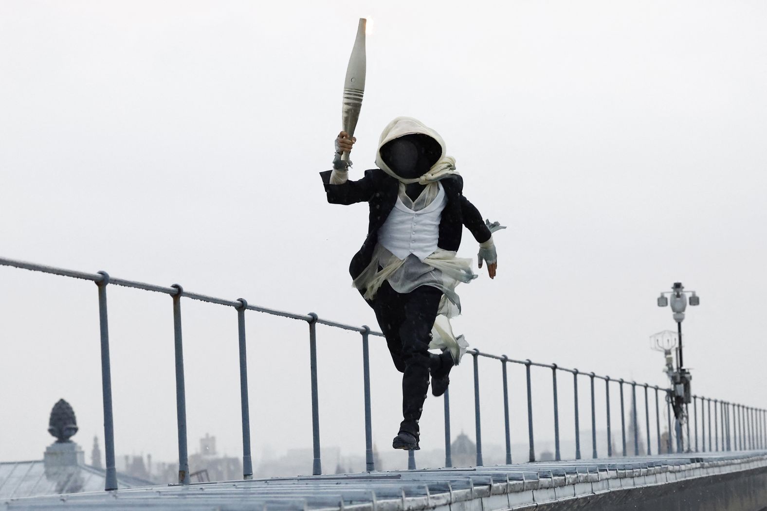 A torch bearer runs atop the Musee d'Orsay during the opening ceremony.