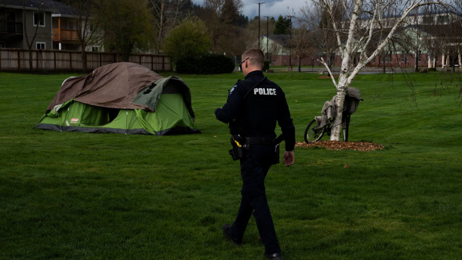 A police officer walks to check on a homeless personon Saturday, March 23, 2024, in Grants Pass, Oregon.