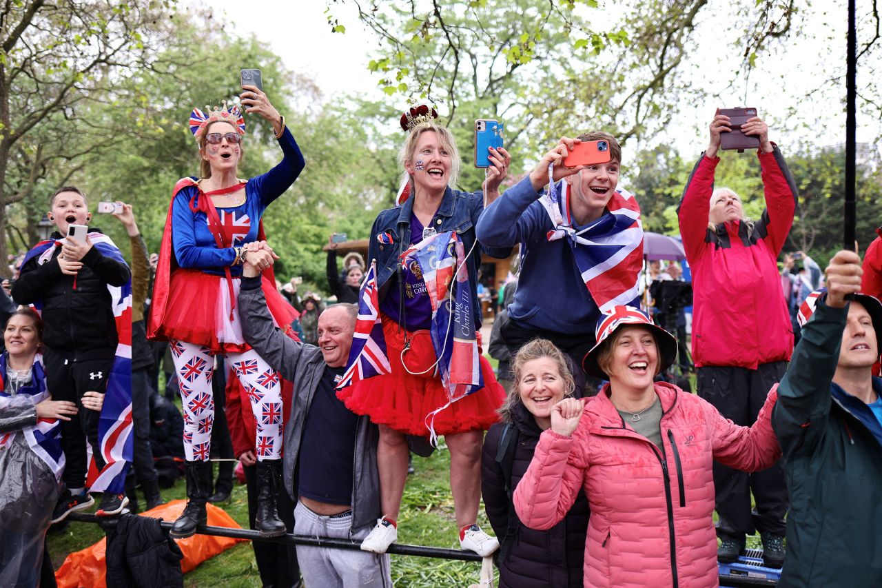 People on The Mall react as King Charles passes them.