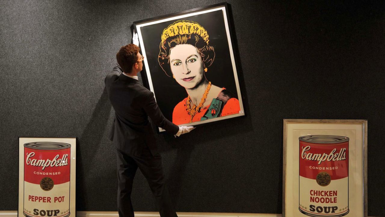 An employee of Bonhams Auctioneers adjusts a print by Andy Warhol of Queen Elizabeth II.