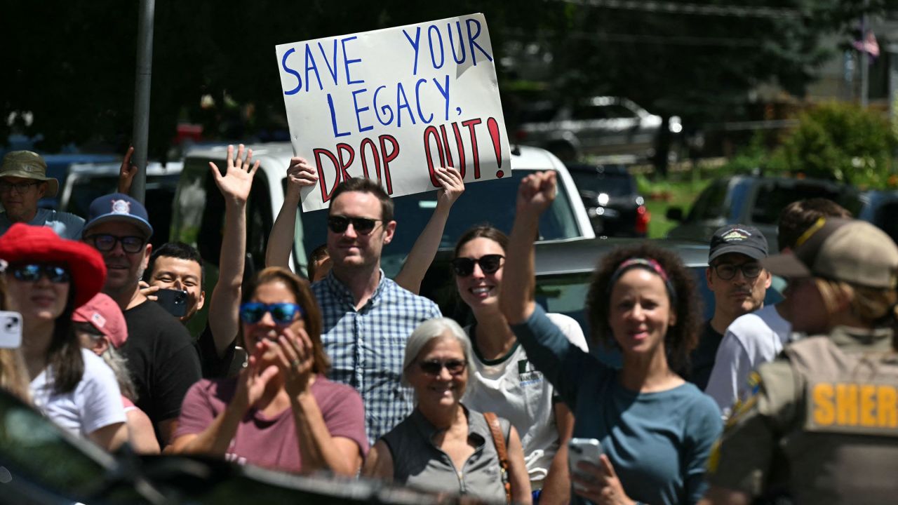 A person holds up a sign encouraging President Joe Biden to drop out of the 2024 presidential race as Biden's motorcade arrives at a campaign rally at Sherman Middle School in Madison, Wisconsin, on July 5. 