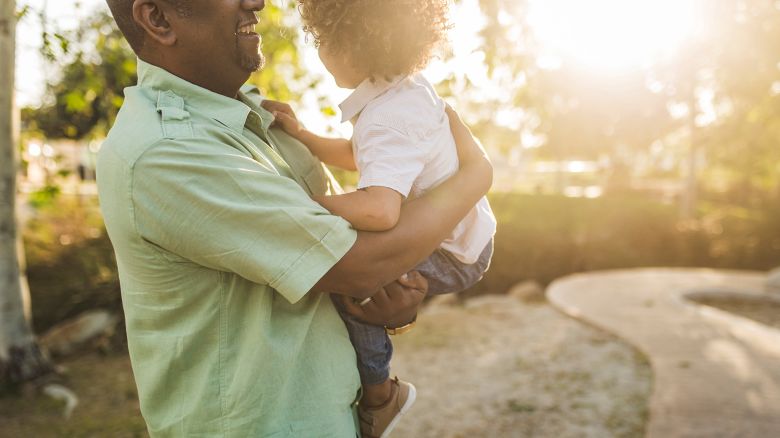 Midsection of happy father carrying son while standing at park