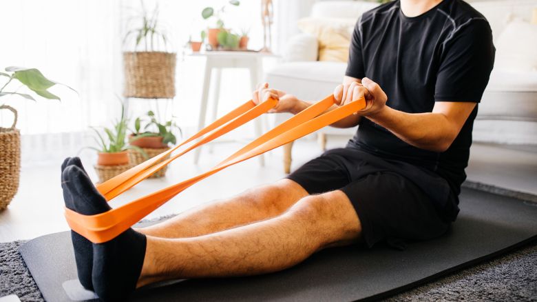 Online training, online video tutorial. Attractive guy in sportswear is using a laptop to watching workout video tutorial at home. He push ups, looks at the screen and repeats the exercises.