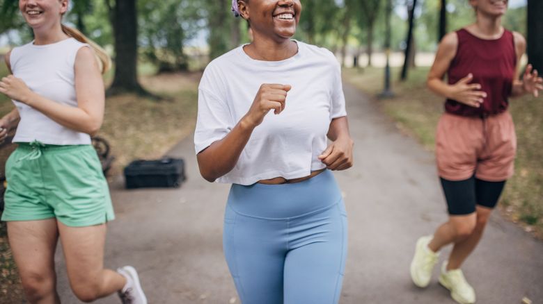 Diverse group of women jogging together on a summer day in public park.