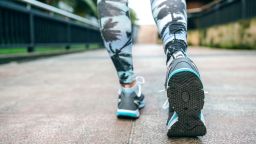 Close up of unrecognizable young woman legs ready to run wearing sneakers and tropical leggings with palm trees