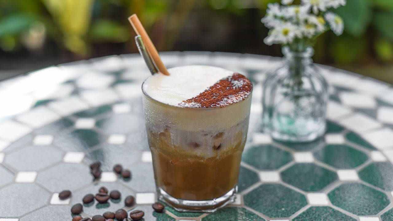 Vietnamese salted coffee with salty cheese cream (ca phe muoi) against green leaves