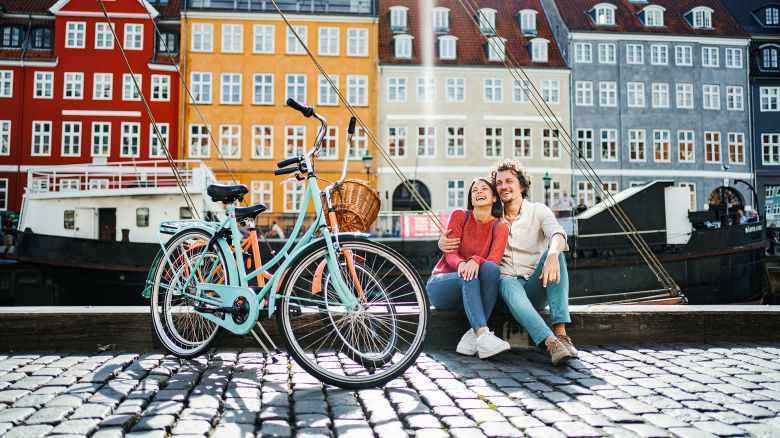 Young romantic couple with their bicycles sitting by the Stromma Canal in Copenhagen