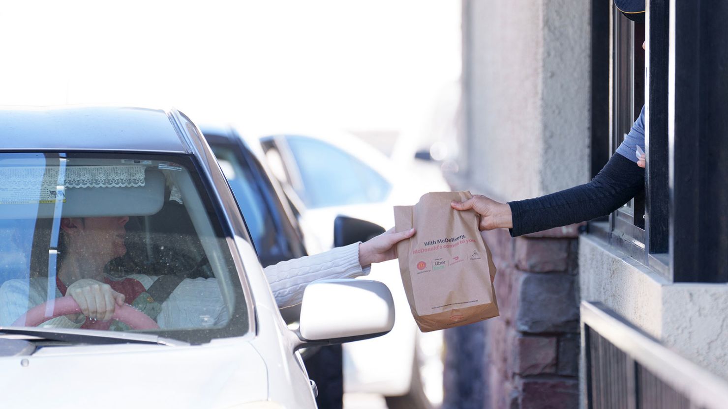 An employee hands a meal order to a customer at the drive-thru of a McDonald's restaurant in California, where the minimum wage for most fast-food workers went up this year from $16 to $20 per hour.