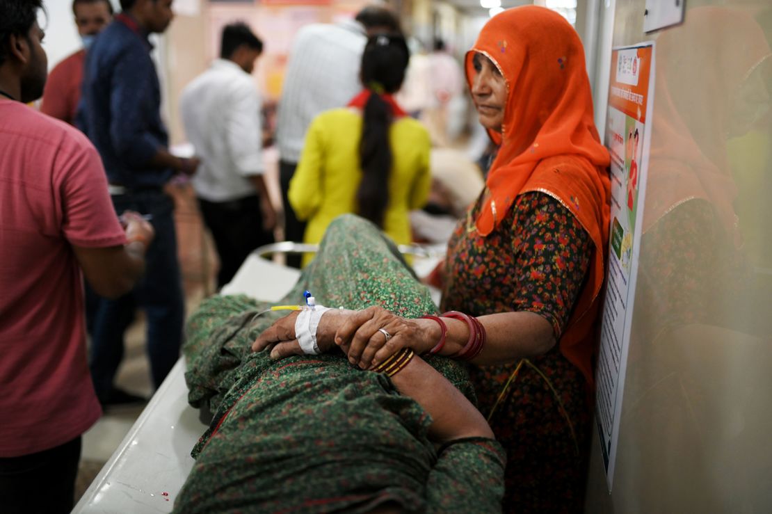 A woman stands beside her family member who is suffering from heatstroke in Varanasi, India, on May 30, 2024.