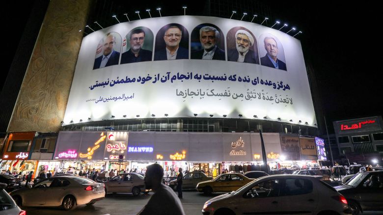 Vehicles move past a billboard displaying the faces of the six candidates running in the upcoming Iranian presidential election in Valiasr Square in central Tehran on June 17, 2024. (Photo by ATTA KENARE / AFP) (Photo by ATTA KENARE/AFP via Getty Images)