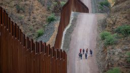 RUBY, ARIZONA - JUNE 24: Migrants seeking asylum from Central and South America walk alongside border fencing after illegally crossing over into the U.S. on June 24, 2024 in Ruby, Arizona. President Joe Biden has announced an immigration relief plan, which promises a path to citizenship for approximately 500,000 undocumented immigrants married to or adopted by U.S. citizens. Day's after Biden's announcement, Republican presidential candidate, former U.S. President Donald Trump announced to a podcast host that he would solidify green cards for foreign nationals who've received a U.S. college diploma. (Photo by Brandon Bell/Getty Images)