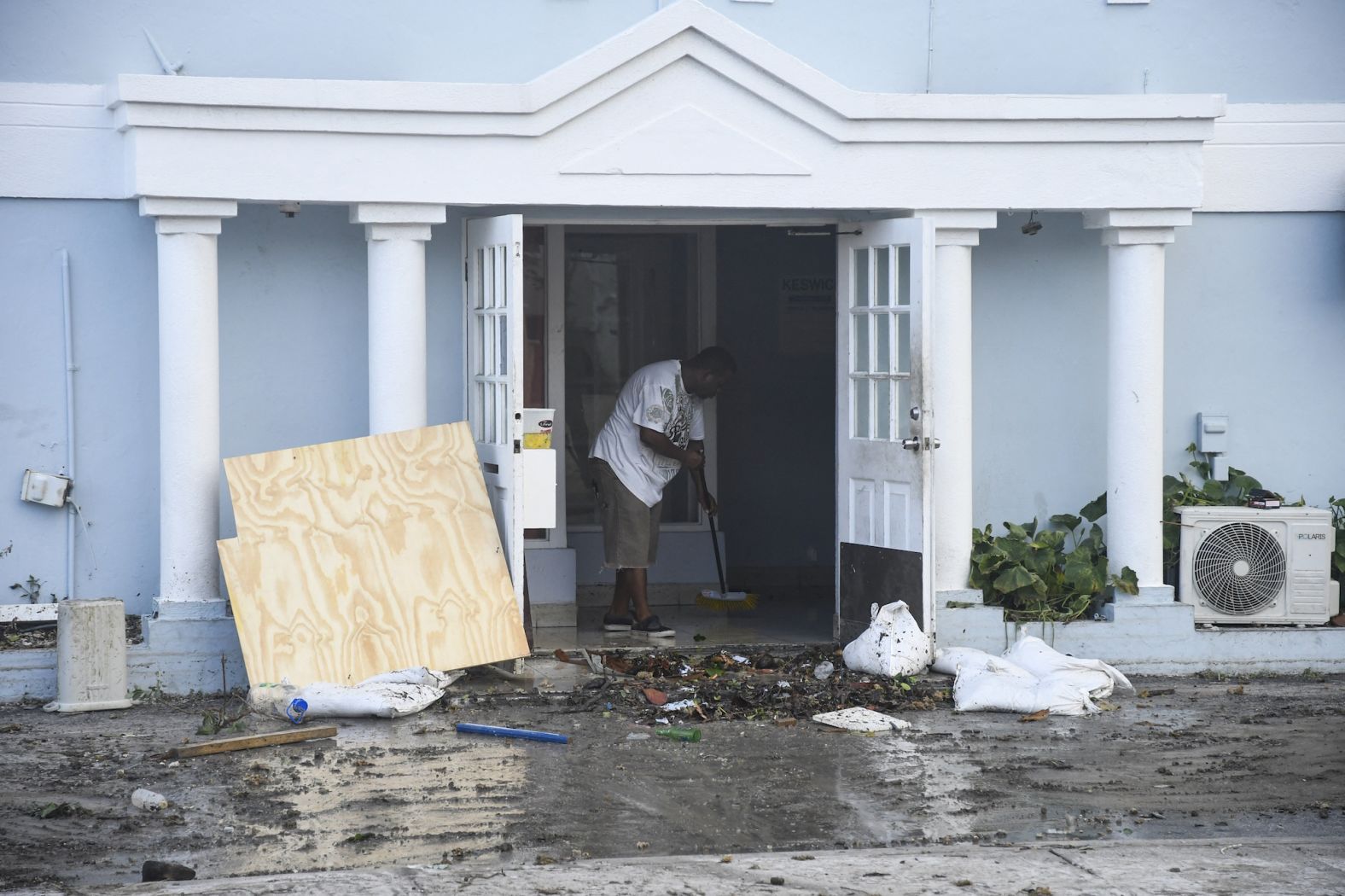 A man clears water from a damaged restaurant Monday in Hastings, Barbados.