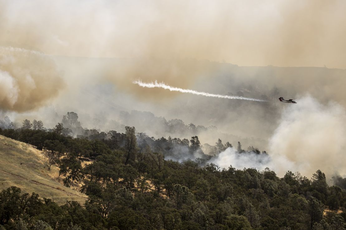 A Cal Fire air tactical aircraft releases a puff of smoke while guiding a fire retardant drop during the Thompson Fire in Oroville, California, on Wednesday.