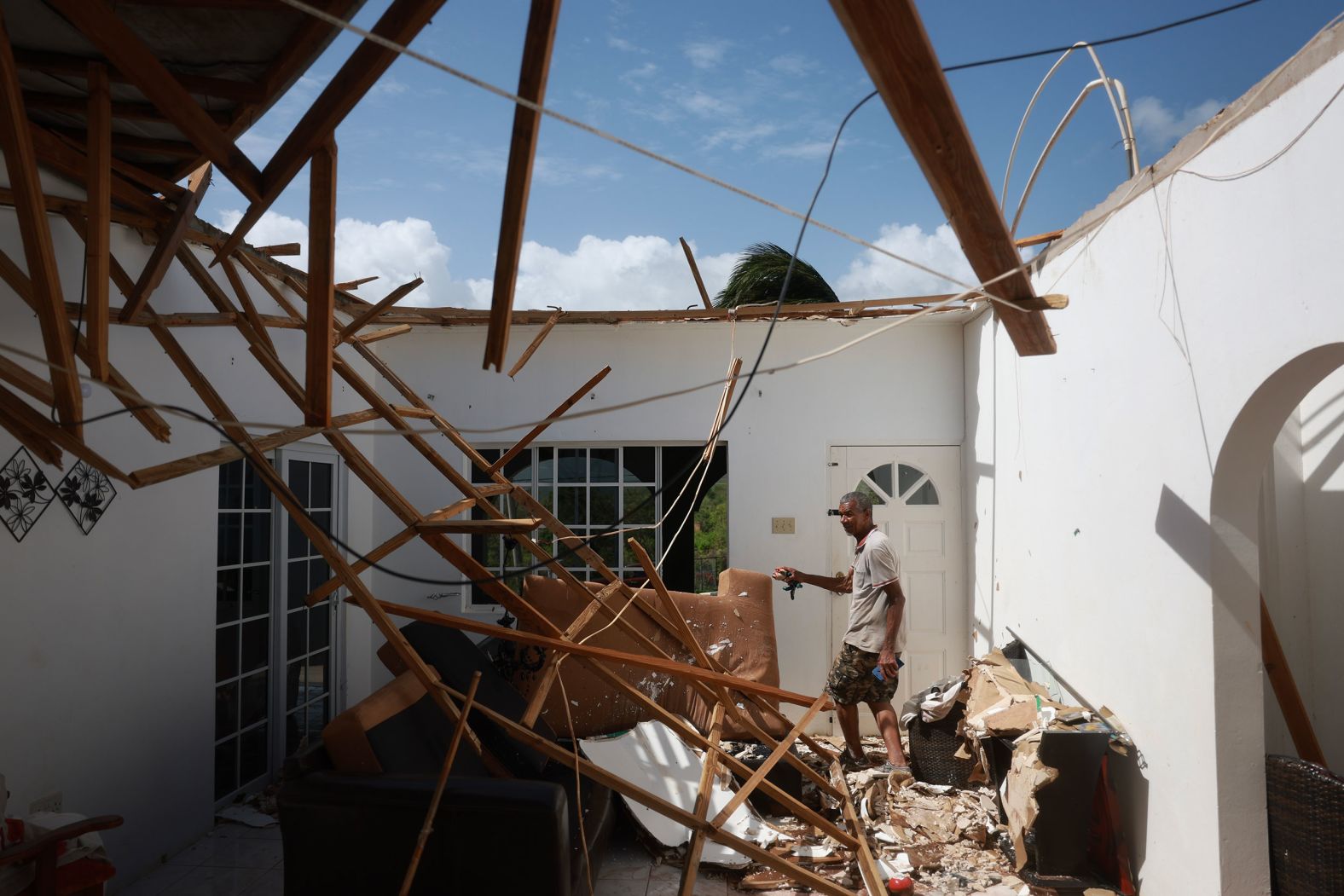 Everton Evanks walks through his living room on Thursday after the roof of the home was blown off by Beryl's winds in St. Elizabeth Parish, Jamaica.