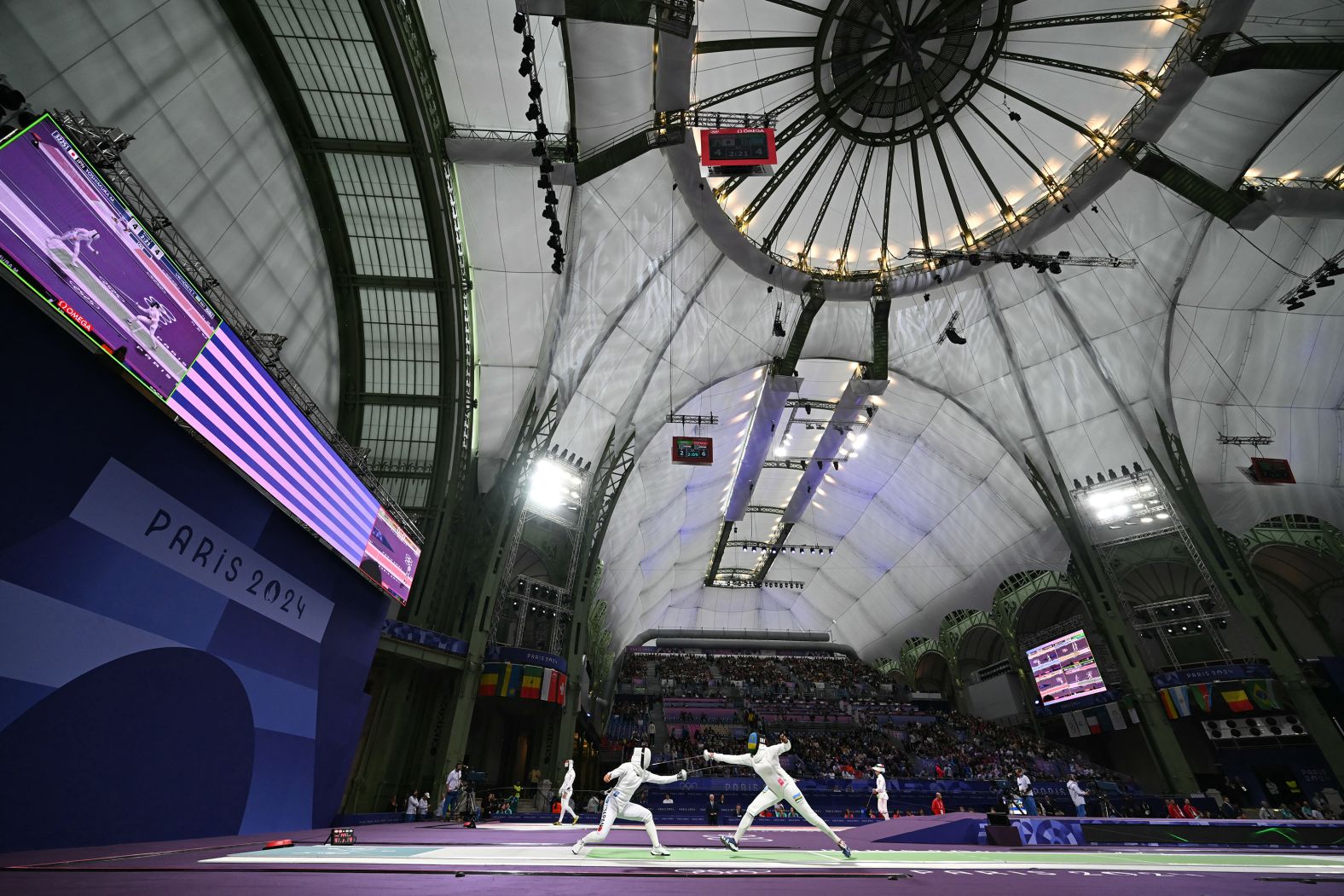 Japanese fencer Miho Yoshimura, left, competes against Rwanda’s Tufaha Uwihoreye in an épée round-of-64 bout on July 27. The Grand Palais, an exhibition hall and event center located off the Champs-Élysées, <a href="https://www.cnn.com/sport/live-news/paris-olympics-news-2024-07-31#h_7a865772de8a4cef656aa98d306ec05c">is the cavernous home to all the fencing competitions</a> at the Paris Olympics.